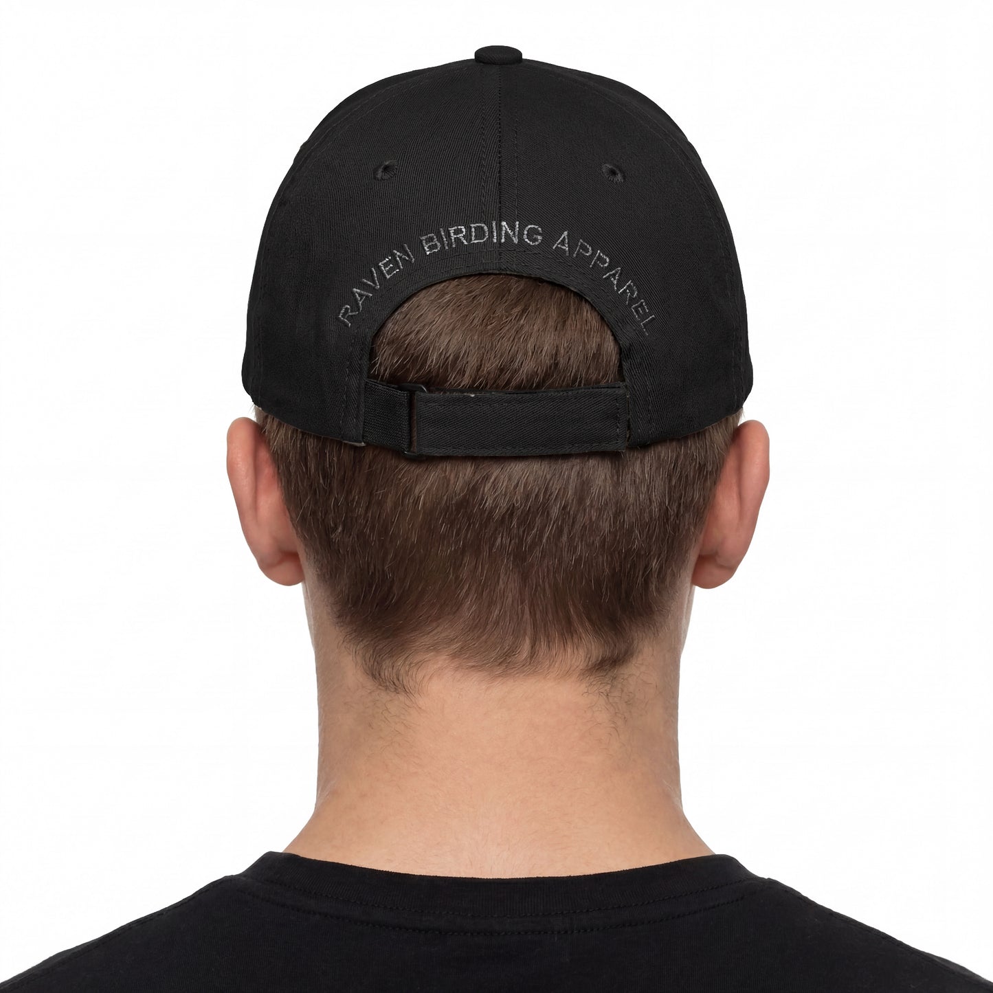 Person wearing a black cap with 'Raven Birding Apparel' branding on the back, on a white background.