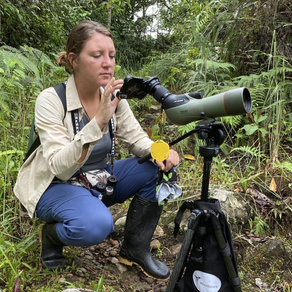 Person setting up a telescope in a forested area