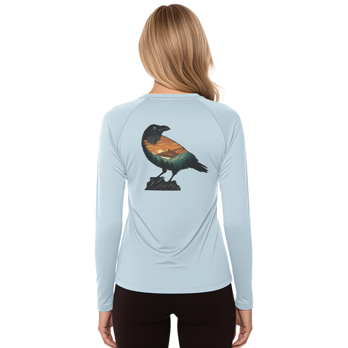 A woman viewed from the back wearing a light blue long-sleeve athletic top with a large raven graphic on the back, paired with black leggings, against a plain white background.