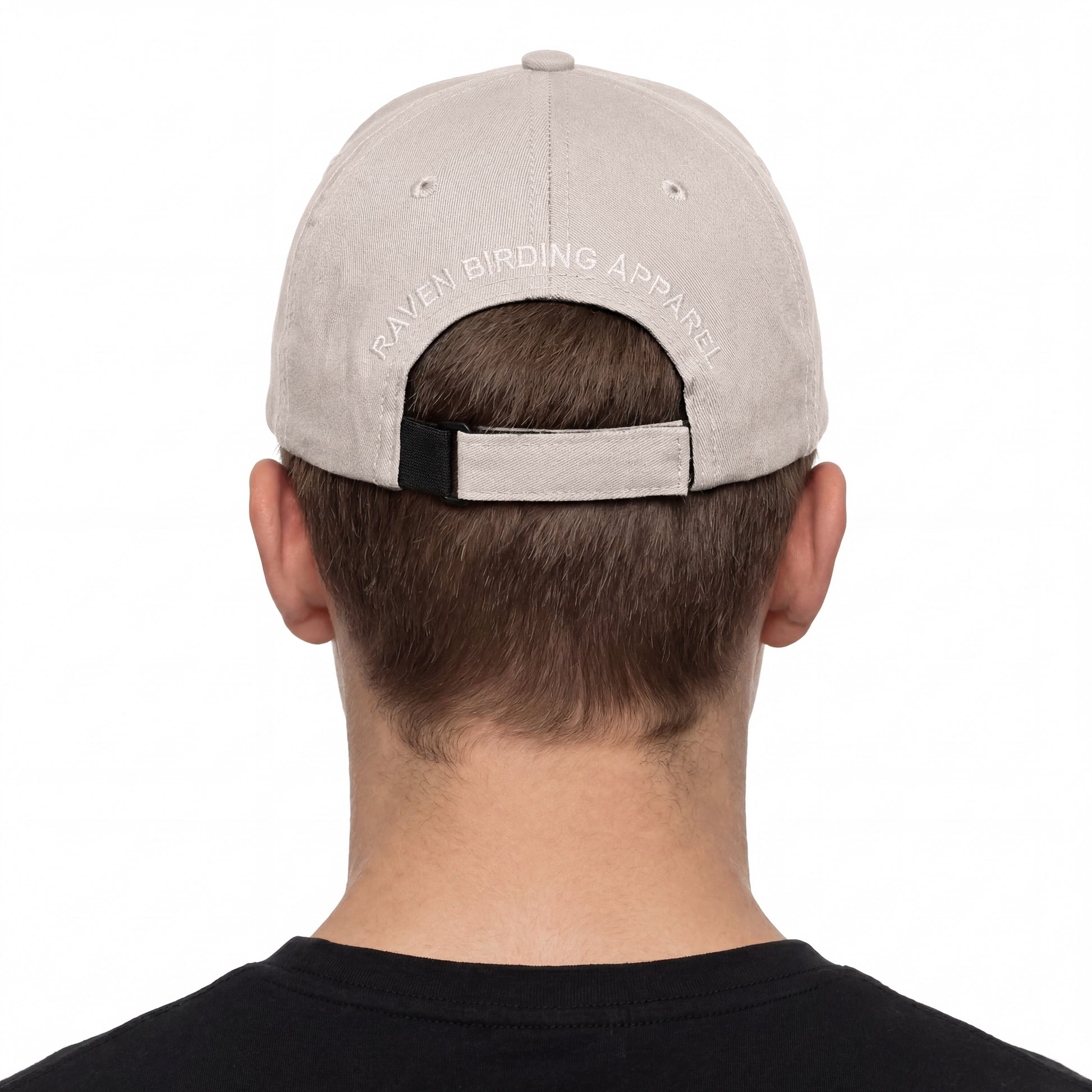 Person wearing a gray cap with 'Raven Birding Apparel' branding on a white background
